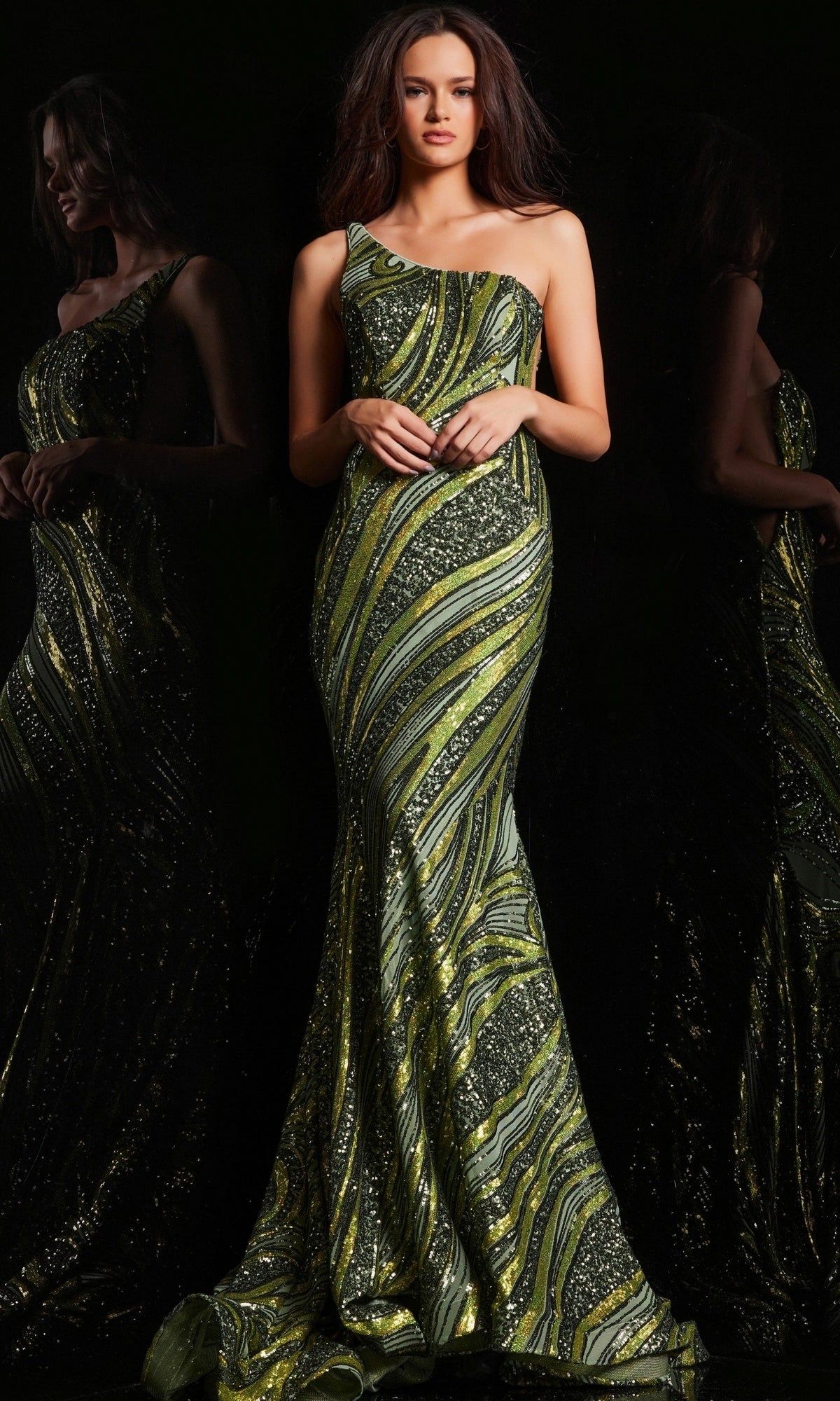 A woman models the Jovani One-Shoulder Long Sequin Prom Dress 24031, featuring green and gold swirling patterns, against a black background with her reflection visible.